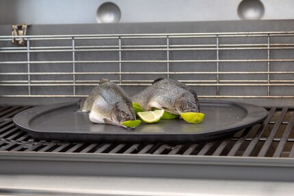 Die zwei kleinen Saiblinge kommen auf einer Limette liegend auf den Grill.