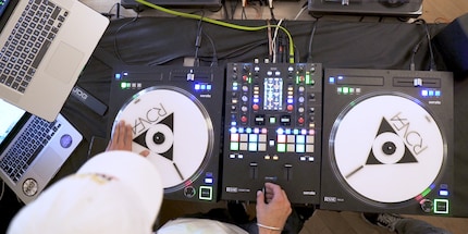 Die weissen Platten sind die Jogwheels. Zwischen Zeigefinger und Daumen hält Ronfa den Crossfader. Dazwischen sind die Knobs und dutzende weiterer Knöpfe.