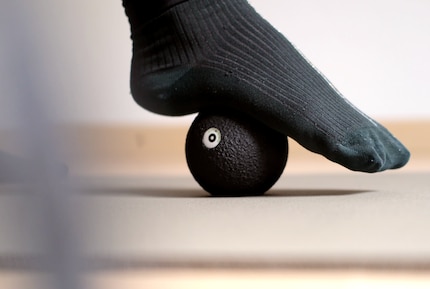 Using gentle pressure, the foot is rolled out over the massage ball.