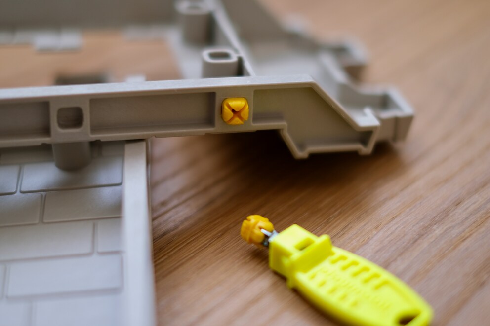 Bei Playmobil werden grössere Mauerteile mit einer Art Plastikdübel verbunden, die zuerst mittels dem gelben Dübeldrücker in die Aussparungen gesetzt werden müssen.