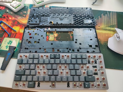Alle drei Teile der MX Mechanical Mini auf einen Blick: oben der Unterteil, in der Mitte der Mittelteil und unten die Deckplatte mit Switches sowie darunterliegender Platine.