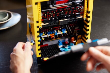 Die Rückseite des Lego-Sets ist abnehmbar. Nicht nur kannst du dir so die Spielmechanik ansehen, auch wartet eine kleine Überraschung auf dich: Ein Mini-Lego-Mensch ist in sein Pac-Man-Spiel vertieft.