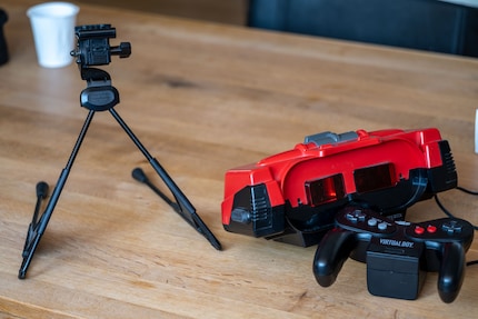 You control the Virtual Boy (right, centre) with a controller (right, bottom). Since it can’t be fixed to your head, you put it on a tripod (left).