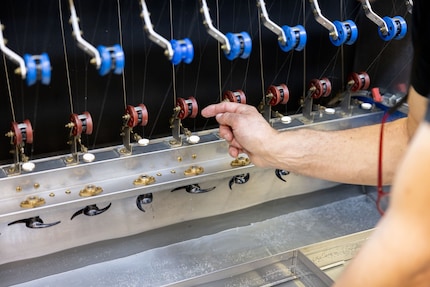 Ein Mensch fädelt die Kokons ein, eine Maschine wickelt sie vollständig ab.