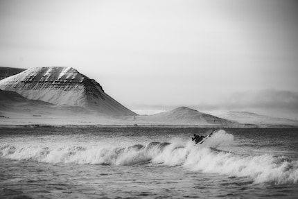 The Icelandic coast as a breathtaking backdrop for surfing in arctic conditions.