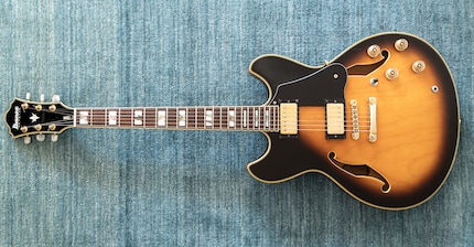 A semi-acoustic guitar, recognisable by its large body and f-shaped holes.
