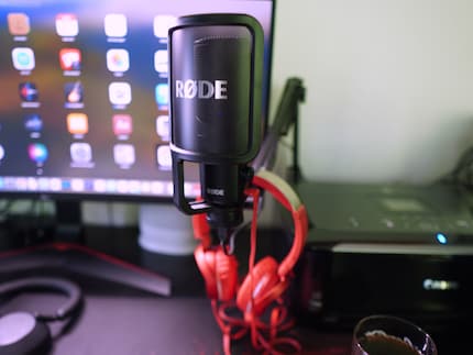 The old, red Sony headphones are always at hand resting on the microphone arm.
