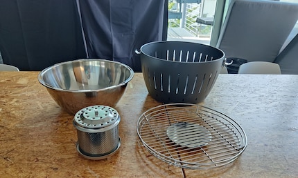 The grill consists of four main components: a cooking grate, charcoal container, inner bowl and outer bowl.