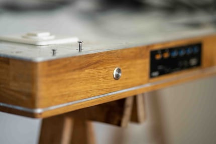 So sieht der Tisch um 180 Grad gedreht aus. Hier erkennst du, dass Holz- und Aluminiumplatten wie ein Sandwich aufeinanderliegen. 