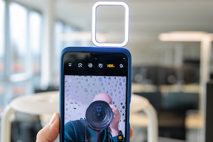 The ring light is reflected in the glasses and camera lenses.
